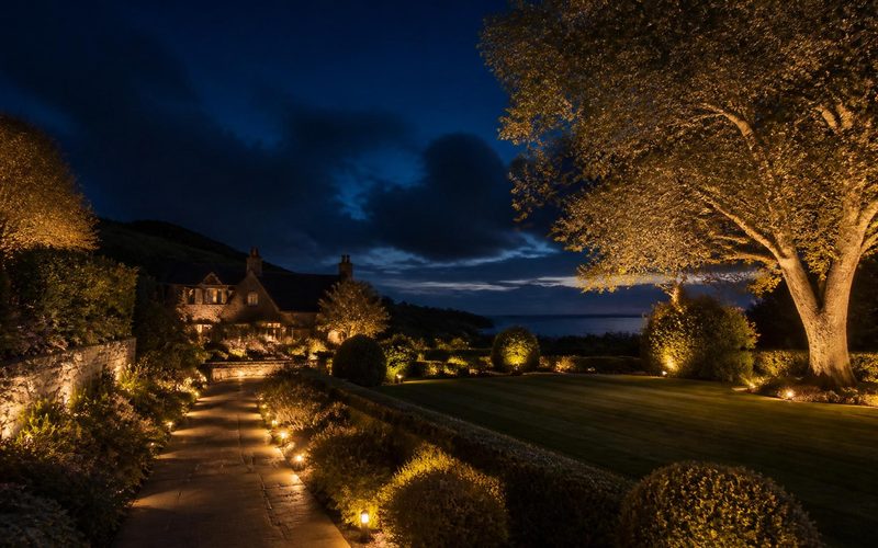 Warm low-voltage LED garden lighting picking out planted borders, a lawn and shrubs in an Eastbourne garden after sundown